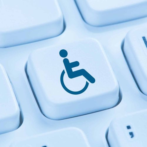 A single keyboard key featuring a blue wheelchair accessibility symbol is surrounded by plain white keyboard keys.