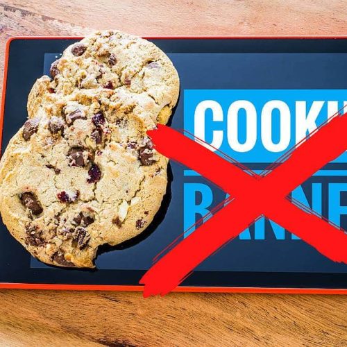 A tablet displays the words COOKIE BANNER, partially obscured by biscuits, with a red X mark superimposed on top.