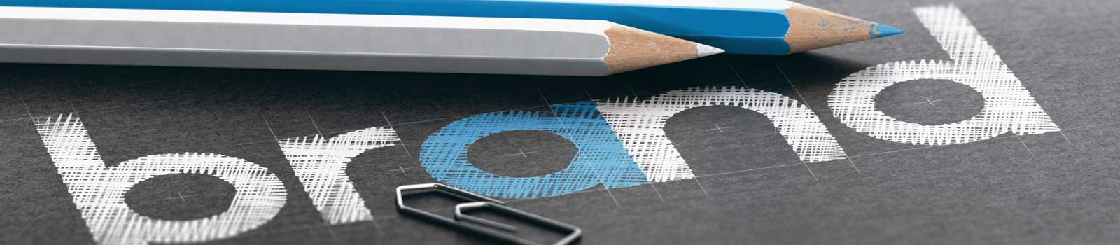 Two pencils and a paperclip rest on a black surface near the word 