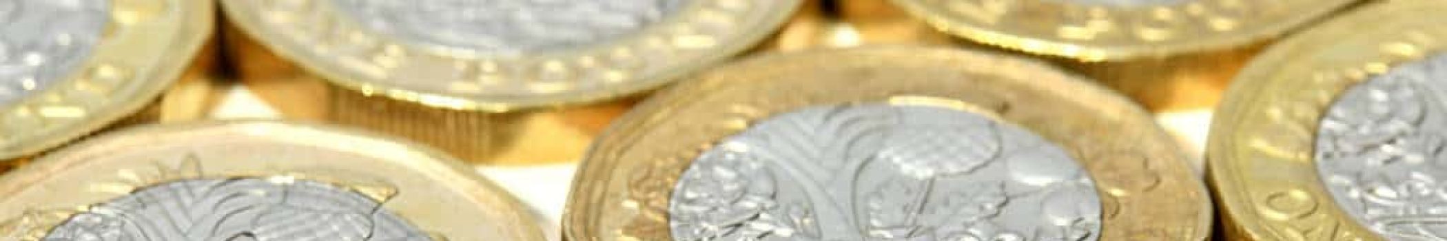 A group of British one pound coins placed side by side, slightly overlapping each other in a tidy pattern.